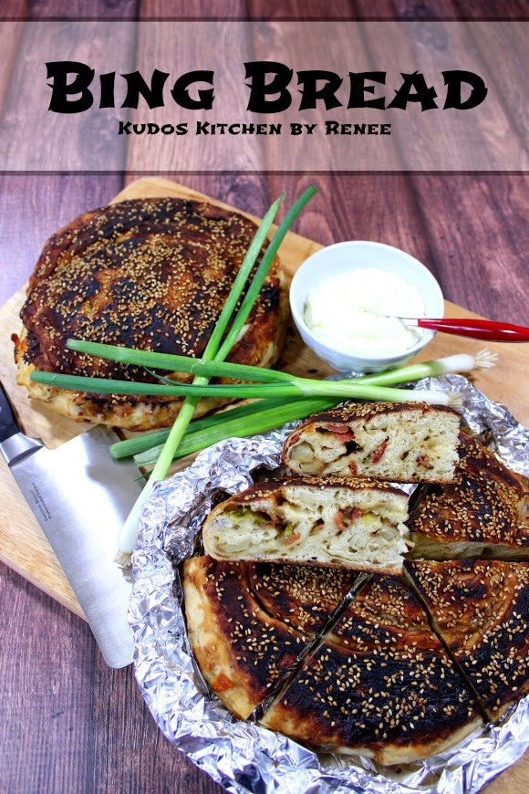 A vertical photo of two loaves of bing bread on a wooden board with scallions.