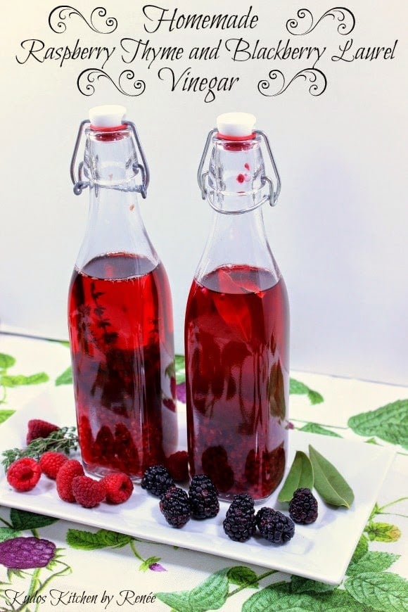 Two bottles of Homemade Berry Infused Vinegar on a white plate with fresh berries on the plate.