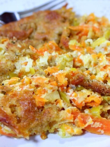 A closeup of a cheesy Carrot and Leek Gratin with a fork in the background.