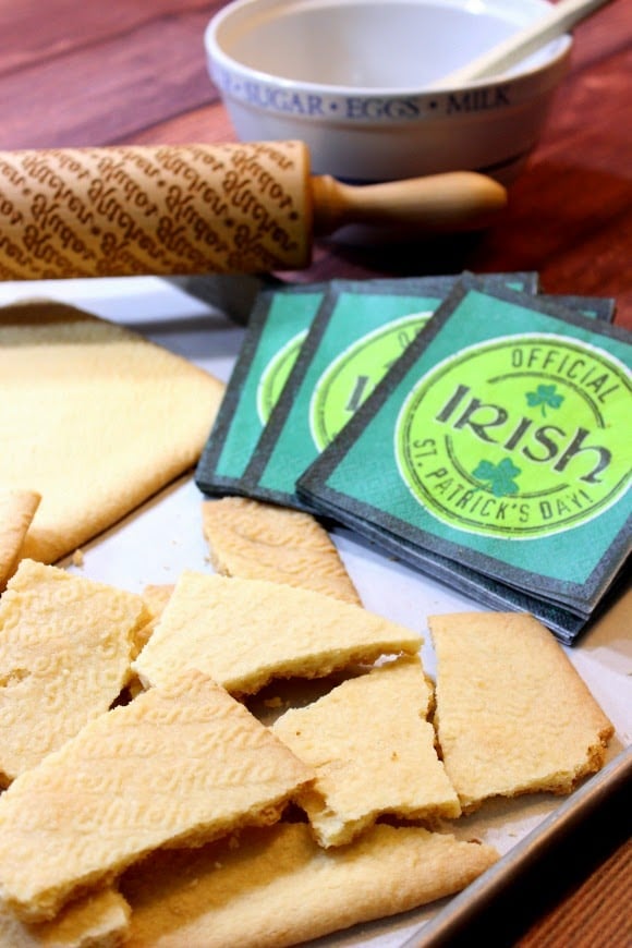 Irish shortbread cookie pieces on a baking tray with a rolling pin and green napkins.