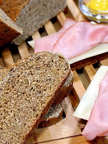 Rye Bread with Dill slices on a bread board along with ham and cheese.