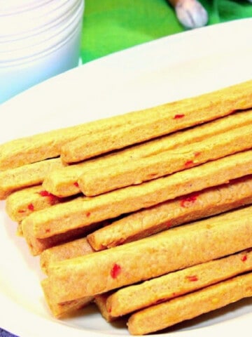 A stack of Pimento Cheese Straws on a white plate with a green background