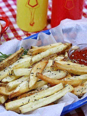 A blue plastic basket filled with Rosemary French Fries and a dish of ketchup