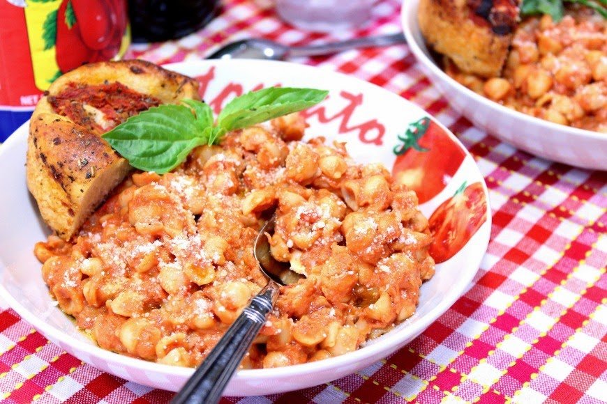 An inviting bowl of tomato bacon pasta with mascarpone, basil leaves, and a spoon.