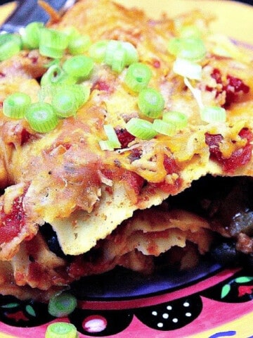 A closeup photo of a slice of Turkey Taco Lasagna with melted cheese and scallions on the top.
