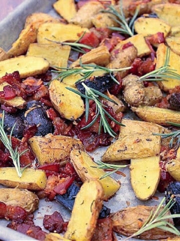 A closeup photo of colorful Bacon Roasted Potatoes with herbs on a baking sheet.