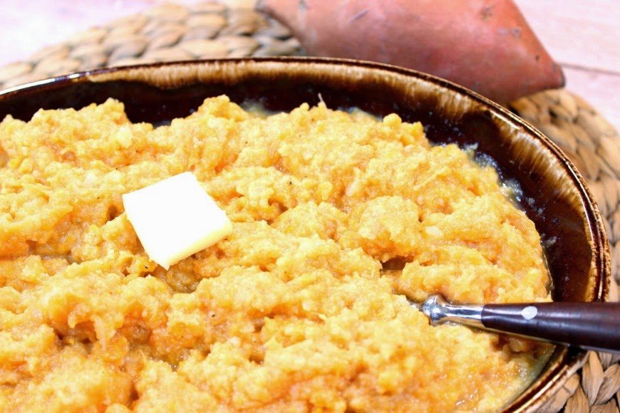 Bowl of Cauliflower Sweet Potato Mashers with a spoon and butter.