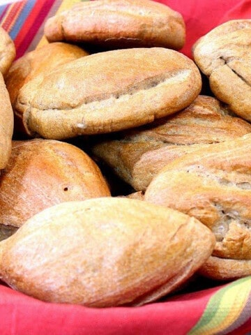 A bunch of Whole Wheat Mexican Bolillios in a bowl with a colorful napkin in