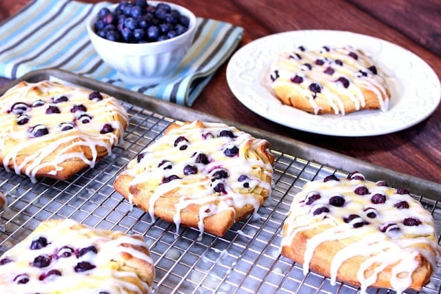 A baking sheet filled with homemade Danish with blueberries and icing