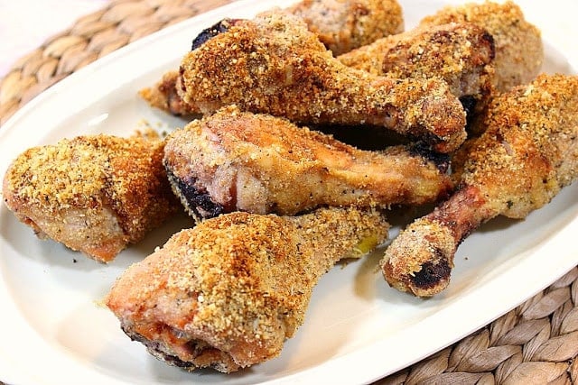 Platter of crispy oven baked chicken legs on a textured place mat.