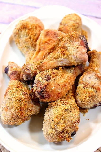 Vertical closeup image of an easy chicken dinner of Italian breaded baked chicken legs piled up on a serving platter.