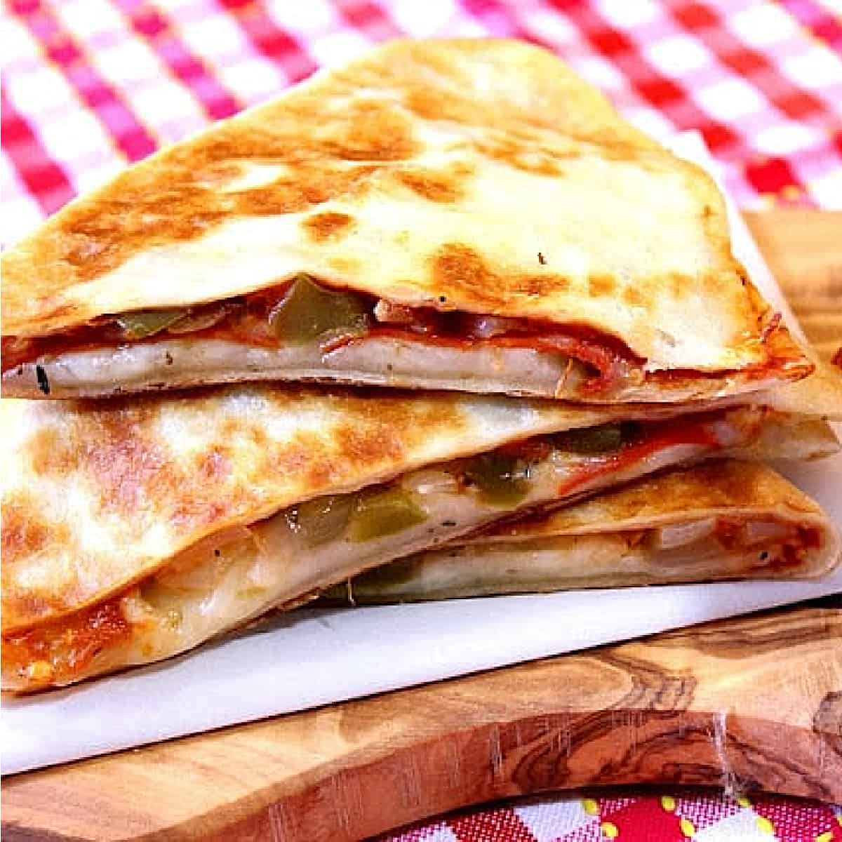 A stack of Pepperoni Pizzadillas with a red and white check napkin in the background.