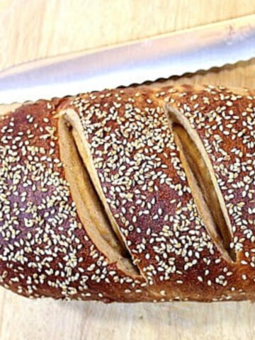Half a loaf of Whole Wheat Dijon Pretzel Bread topped with sesame seeds.