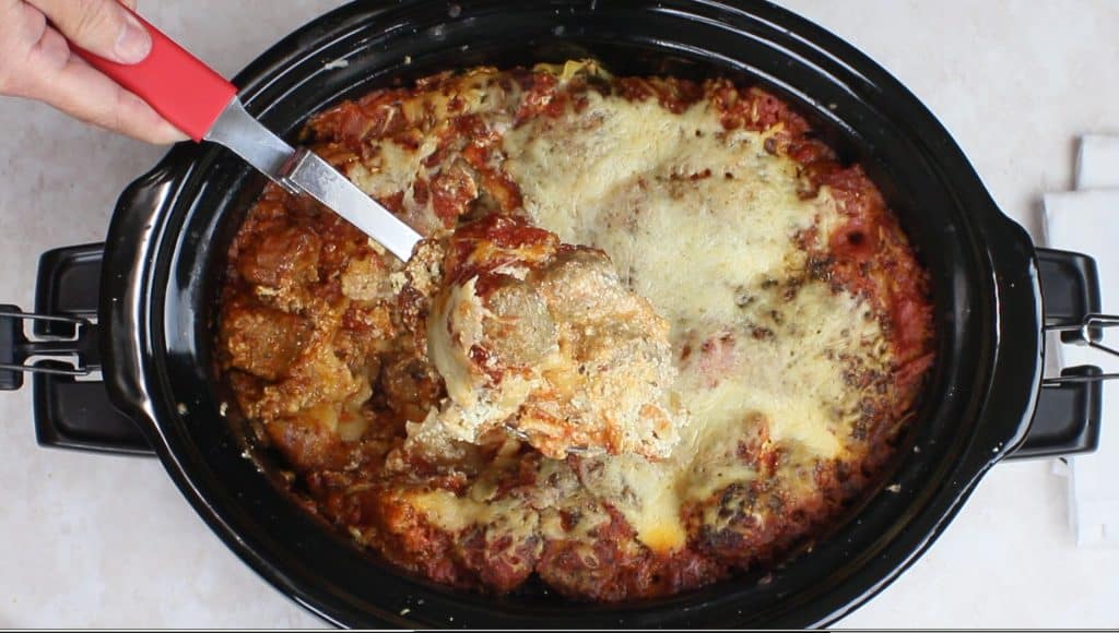 Slow Cooker Meatball Lasagna in a crockpot with a serving spoon.