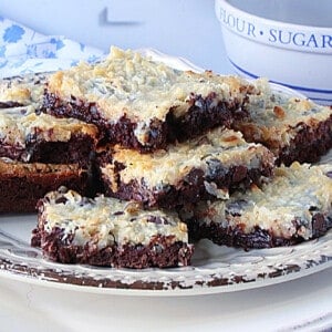 Coconut Brownies on a plate with melted chocolate and nuts.
