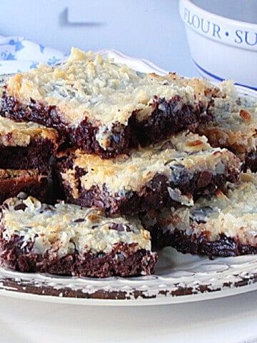 Coconut Brownies on a plate with melted chocolate and nuts.