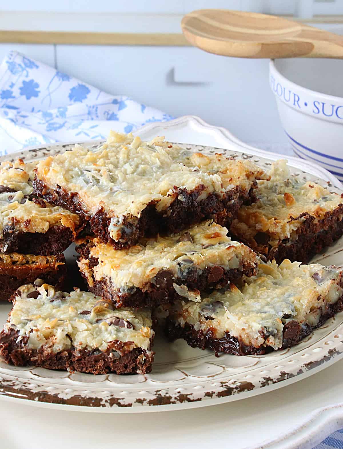 A plate of Coconut Brownie Bars with a blue and white napkin in the background.