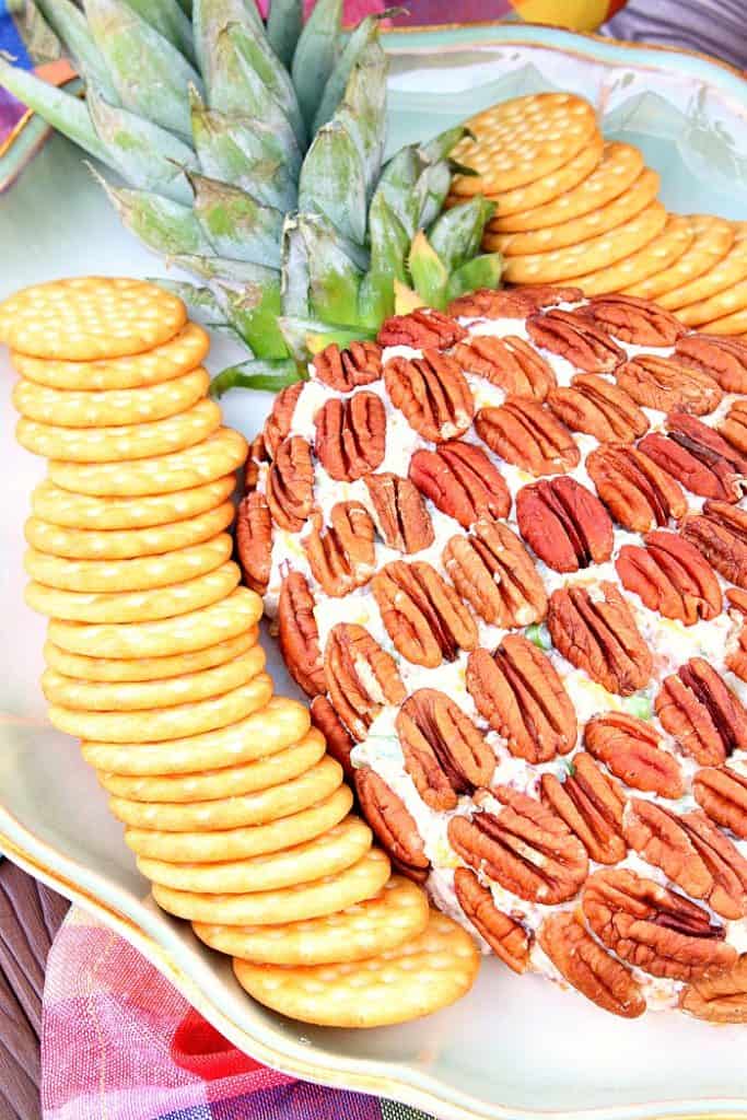 Closeup photo of a pineapple cheese ball with pecans and crackers