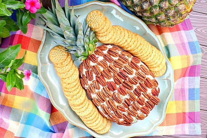 Overhead photo of a pineapple cheeseball on a platter with crackers.