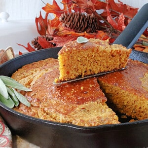 A triangle slice of Pumpkin Cornbread with Sage in a cast iron skillet.