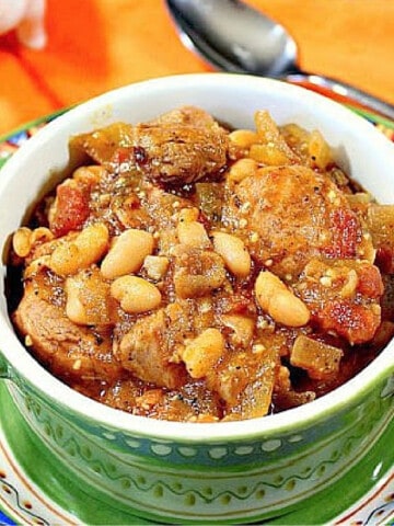 A green crock filled with Pork Cassoulet with beans and sausage.