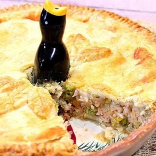 A whole Pork Pot Pie with a slice taken out and a pie bird in the center.