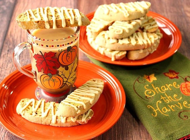 A coffee mug with a few Pumpkin Banana Biscotti Cookies perched on top.