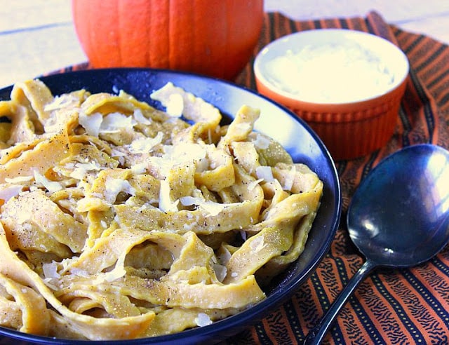 Homemade Pumpkin Pasta with Sage in a black bowl covered with Parmesan.