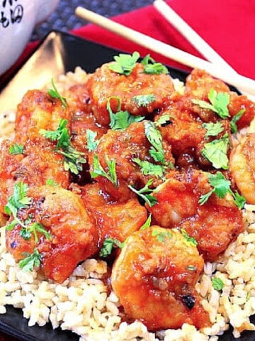 Sweet Chili Shrimp on a bed of rice with cilantro and chopsticks on the side.