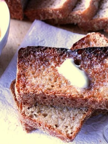 Two slices of toasted Whole Wheat English Muffin Bread with butter on a napkin.