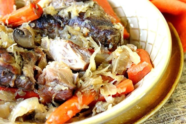 Closeup photo of a bowl of German Pork Ribs and Sauerkraut with carrots and mushrooms