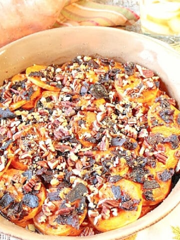 Bourbon Baked Sweet Potatoes in a round casserole dish with overcooked bacon on top.