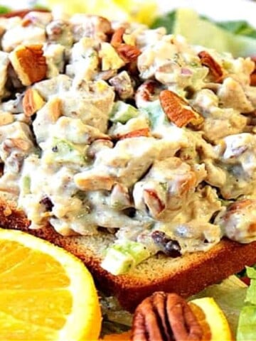 A slice of bread topped with orange cashew chicken salad with pecans and fresh oranges and lettuce.