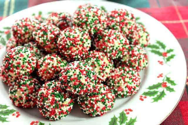 A horizontal image of a plate of cream cheese sprinkle cookies on a festive Christmas plate.