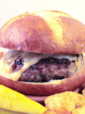 A closeup of a Dilly Swiss Cheese Burger with melted Swiss cheese and a golden brown bun.