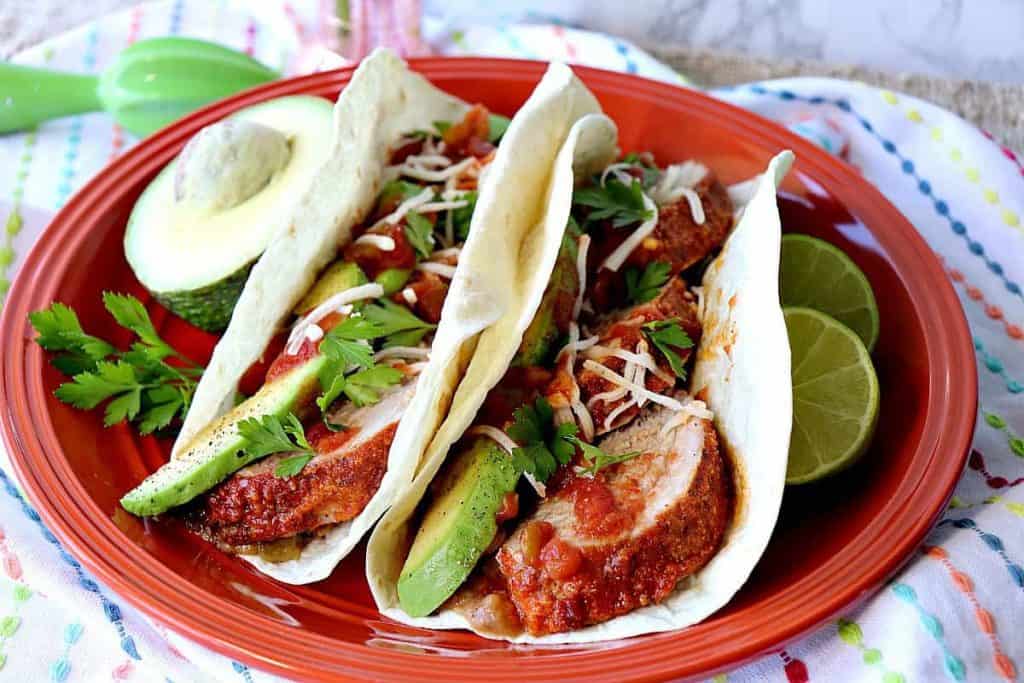 Lime Marinated Pork Tacos on an orange plate with limes. - 