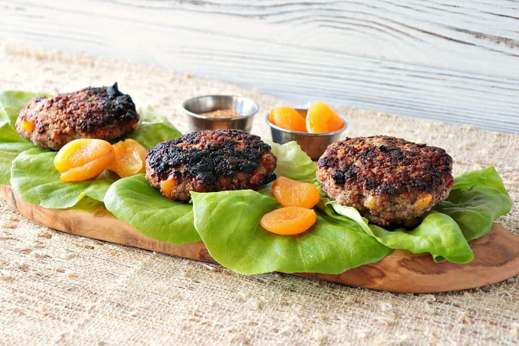 Three pork burgers with dried apricots and lettuce leaves. 