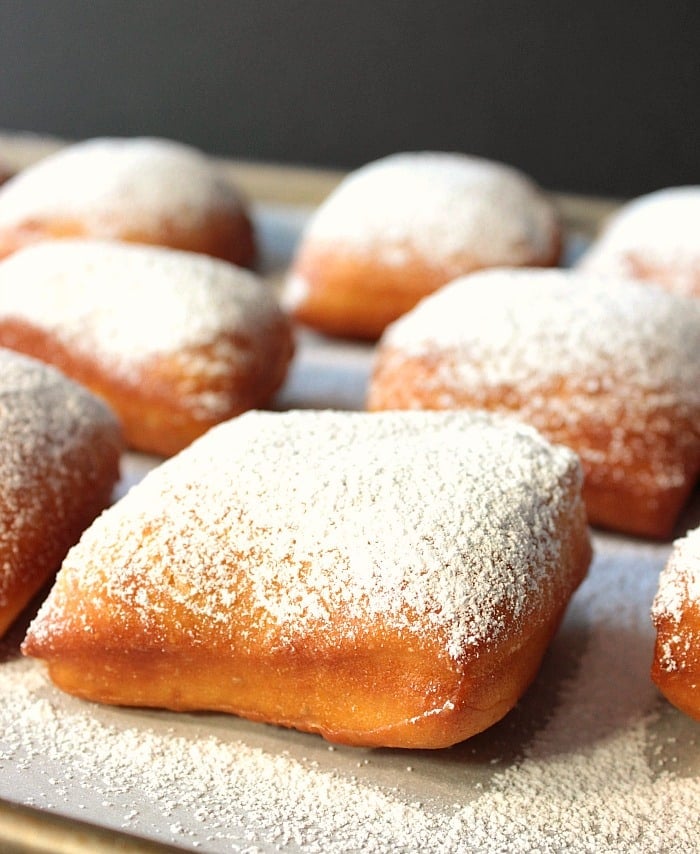 Closeup picture of a square beignet with powdered sugar dusting.