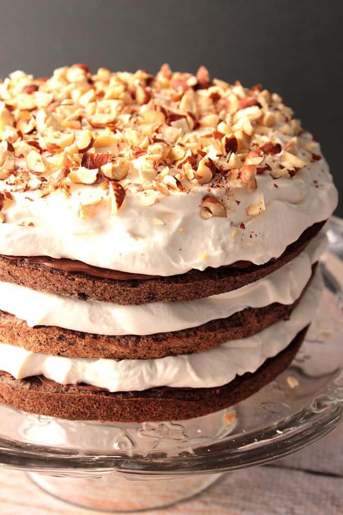 Chopped Hazelnuts top a chocolate cake with whipped cream.