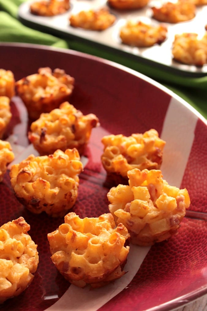 A closeup photo of a bunch of Macaroni and Cheese Appetizer Bites on a football platter.