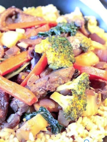 Beef, Broccoli, Bok Choy on a plate with rice and carrots.