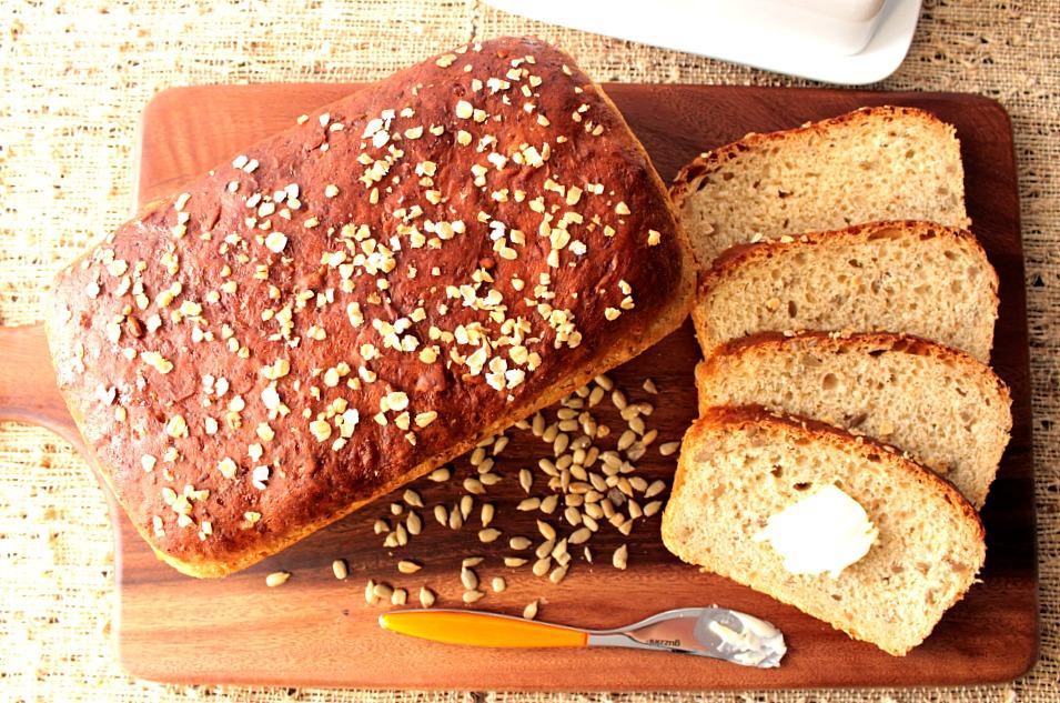 Overhead photo of a loaf of oatmeal honey bread with a few slices on a cutting board.