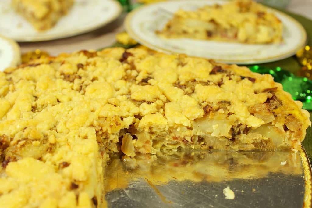 Irish Cheese and Potato Tart with slices taken out and the slices in the background on china plates.