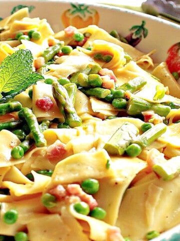 An offset photo of a flat bowl filled with Pappardelle with Spring Vegetables of asparagus and peas.