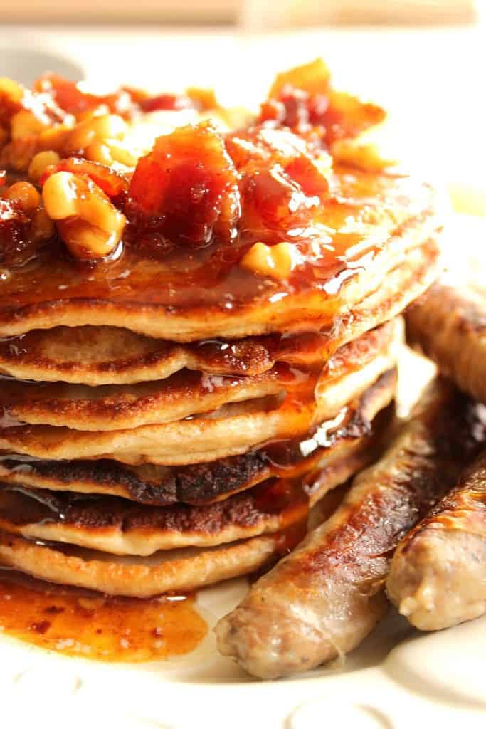 A stack of Whole Wheat Banana Bourbon Pancakes with walnuts and syrup.