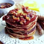 A stack of Banana Bourbon Pancakes with Walnut Bacon Maple Syrup on top.