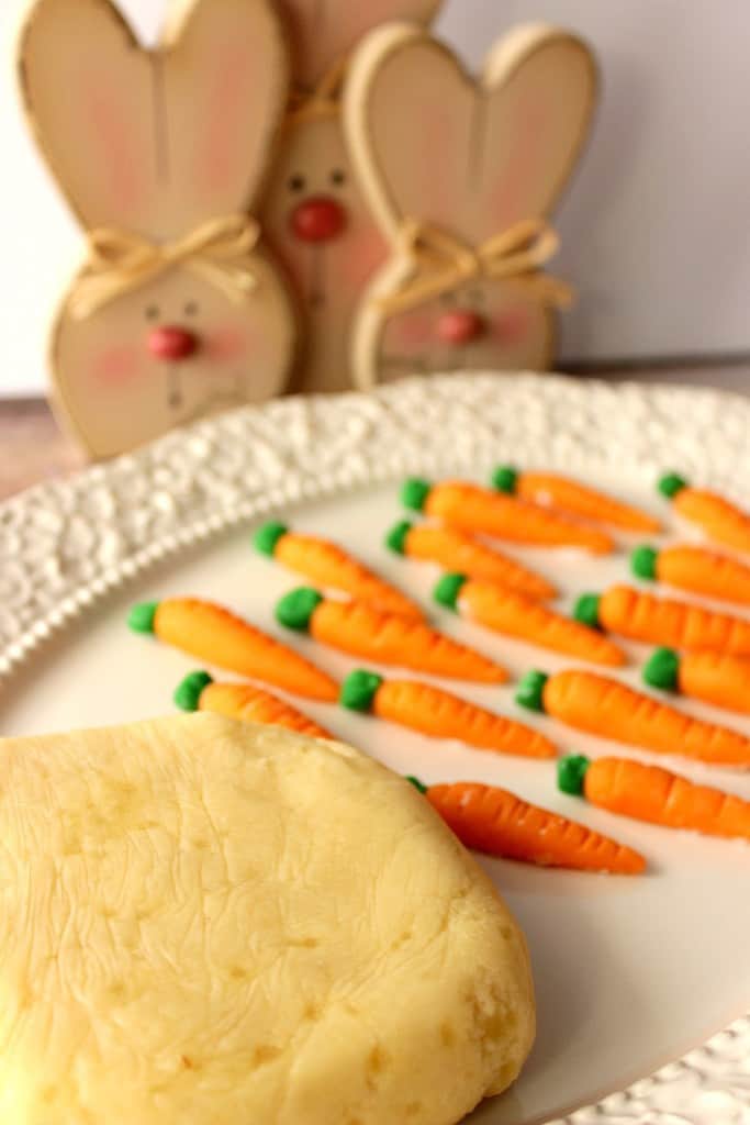 Block of marzipan candy on a plate with orange and green marzipan carrots.