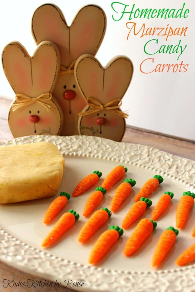 Homemade Marzipan Candy Carrots on a white plate along with a block of homemade marzipan with bunnies in the background.