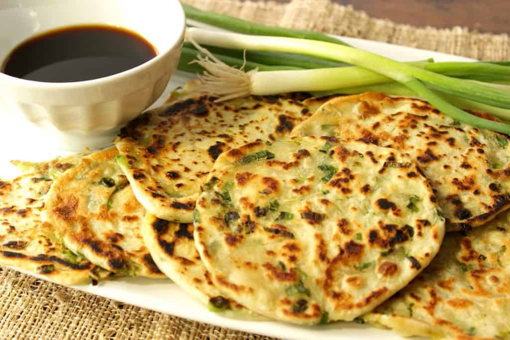 Savory Scallion Pancakes are thinly rolled pancakes that are packed full of chopped scallions. Serve them as an appetizer or side dish along with your favorite Asian dipping sauce. - Kudos Kitchen Asian Scallion Pancakes