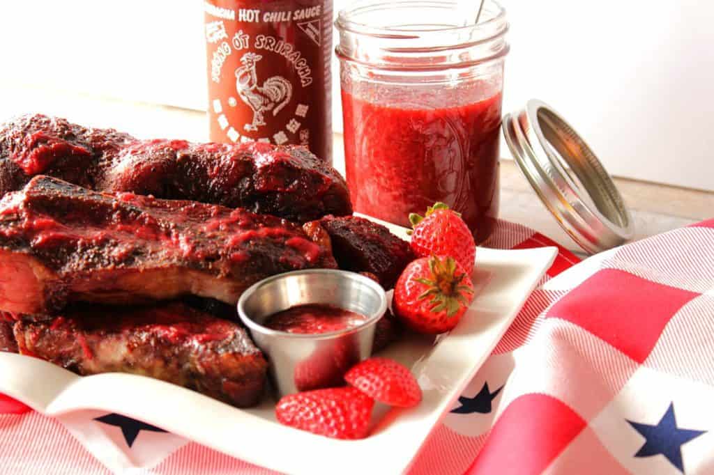 Ribs on a white plate with strawberry BBQ sauce
